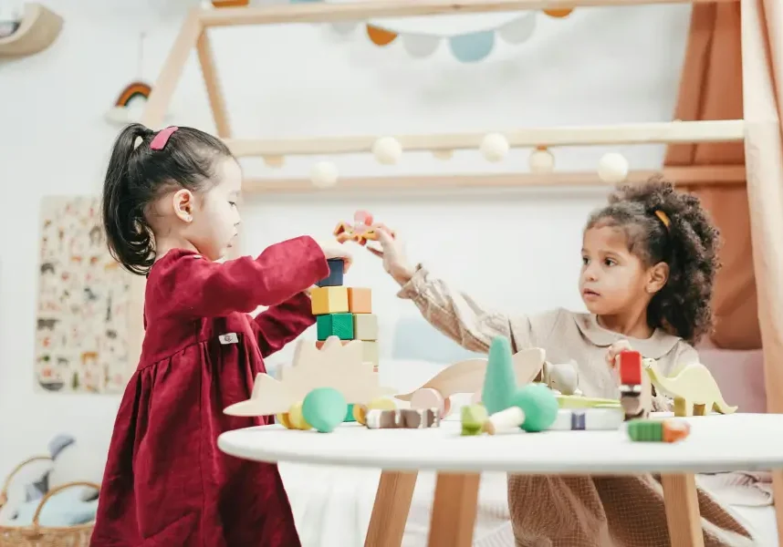 toddler girls playing with wooden blocks